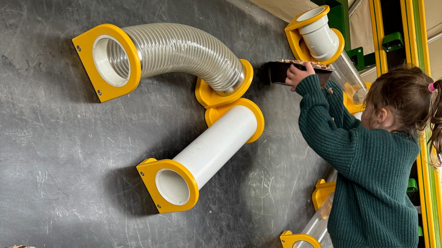 Child playing with grain drop depot developed by Heemer Crafted